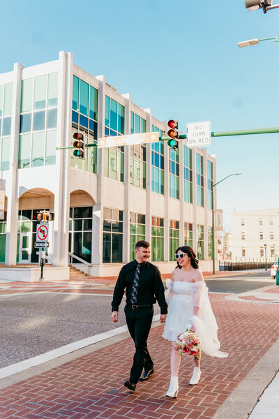 Bride and groom walking through a city crosswalk in downtown Martinsburg during their fun and modern elopement