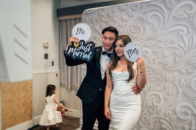 Couple holding wedding photo booth props at their reception