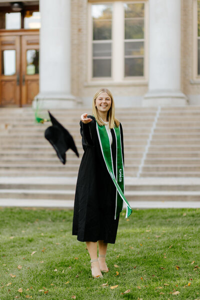 Colorado State University graduate celebrating by throwing her cap at the camera during a photo session at The Oval in Fort Collins, Colorado.