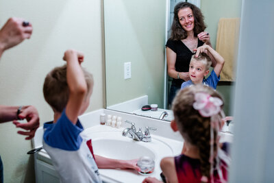 A little boy in front of a mirror having showing to his mom how the arrange his hair