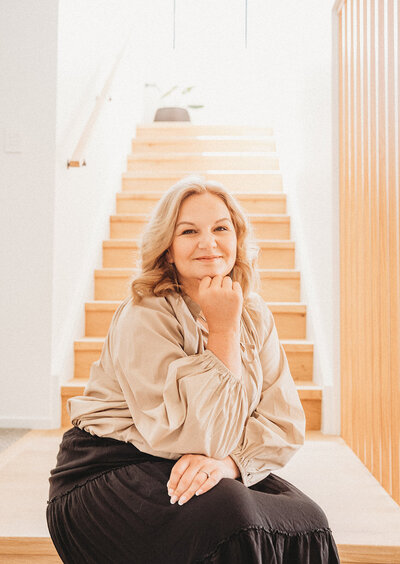 Personal brand image of confident interior designer posing in front of light filled staircase