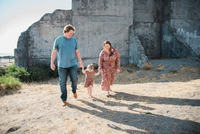 Family walking between concrete structures at Chambers Bay park for summer family photos
