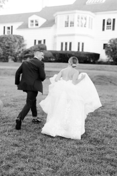 Black and white timeless photo of bride and groom running.
