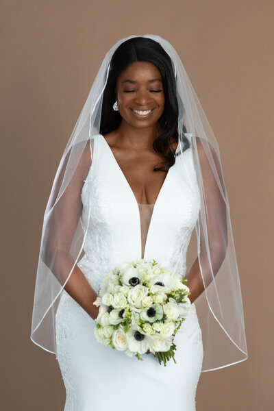 bride wearing a short ribbon edged veil and holding a bouquet