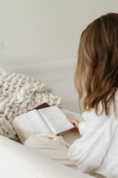 Woman reading on a cozy sofa, symbolizing peaceful family counseling sessions for parenting, adoption, and communication support in Brentwood, Tennessee at For the Sheepish