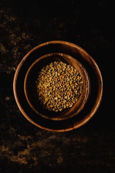 two nested bowls, smaller bowl filled with bee pollen, aerial view with dark bacldrop