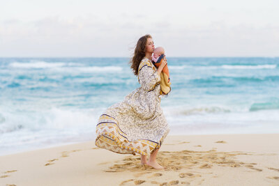 A mother carrying her son at Baldwin Beach sunrise session with Mariah Milan.