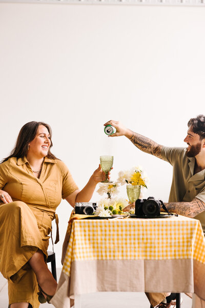A person leaning over their partner's shoulder while they sit in a chair