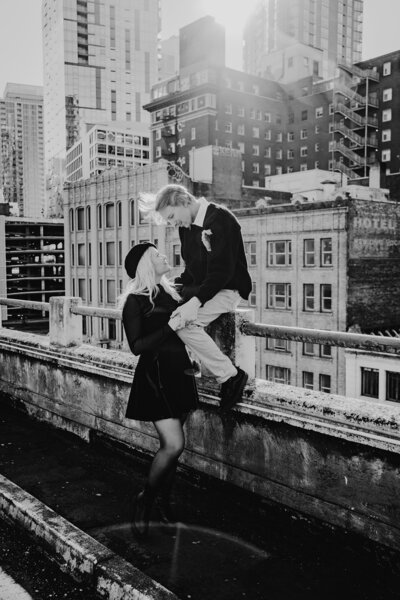 a couple on top of a Seattle  parking garage looking at each other with Seattle in the background