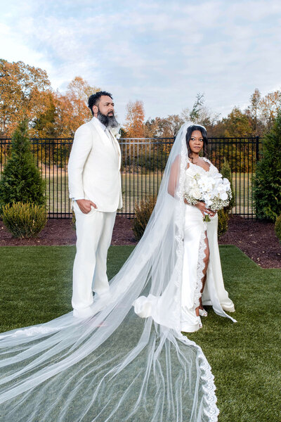 Romantic outdoor wedding portrait with the bride’s veil flowing in the breeze.
