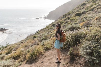 woman walking on trail next to ocean