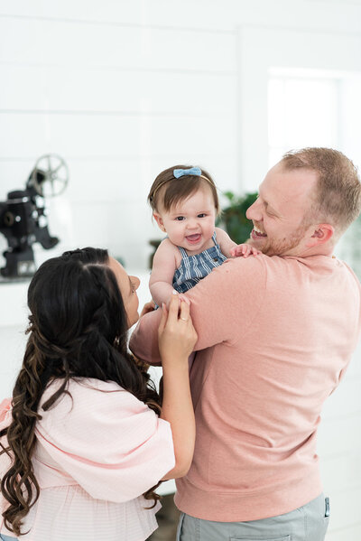 mom dad and baby playing over dads shoulder by miami maternity photographer msp photography David and Meivys Suarez