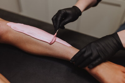 Esthetician spreads hard wax on client's leg