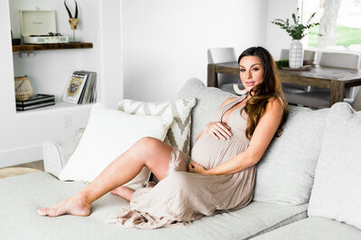 pregnant woman sitting on couch for lifestyle maternity session