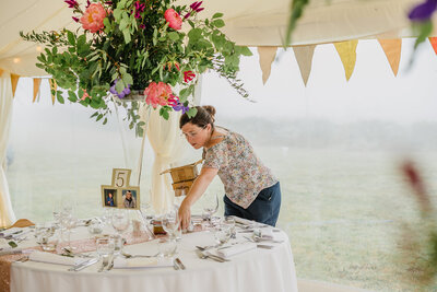 Anna Sawles team putting out items on the wedding breakfast tables for this Cornwall marquee wedding