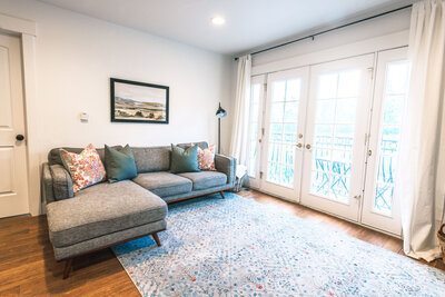 A  large gray sectional and doble doors leading to the deck