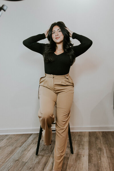 Valeria Savvadera with hands in hair soft smiling, and posing for headshot at Heath Hair Salon and Spa.