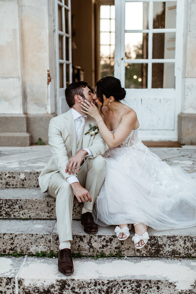Married couple kissing under colourful flower arch