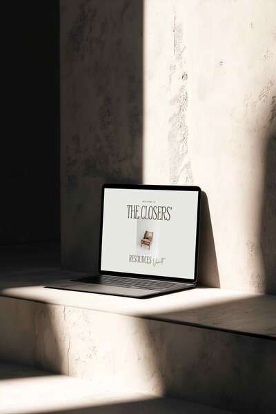 Laptop displaying The Closers’ Resources Vault welcome page, featuring minimalist design with neutral tones and modern typography, positioned in soft natural light.