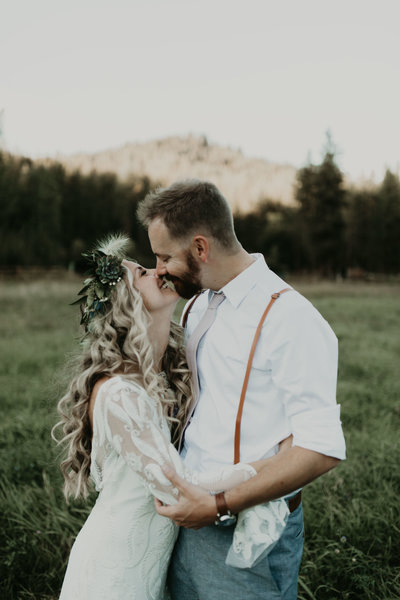 Bohemian bride smiles lovingly at her groom in the fields of the Mountain Springs Lodge in Levenworth, WA