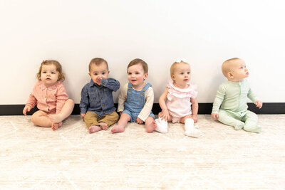 Babies sitting in a row in the playroom