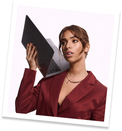 Polaroid of a woman in a red blazer holding up her Mac laptop as she strategizes for her social media clients.