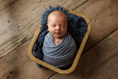 tan baby boy sleeping on a fern back drop with a white and green bonnet in his posed studio newborn session in harrisburg