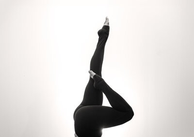 Black and white image of Alex Paige in a yoga pose with one arm and one leg on the ground