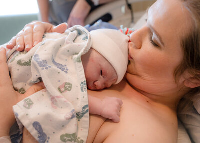 Mother kisses her new baby at the hospital.