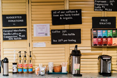 coffee bar with syrups and coffee signs hanging on the wall
