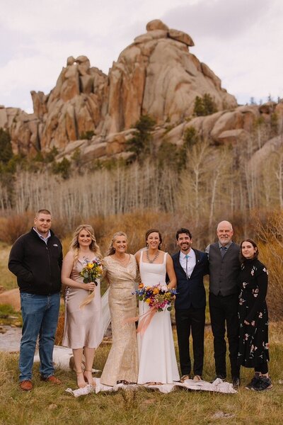 family at a wedding with bride and groom in the center rocks and fall scenery in background