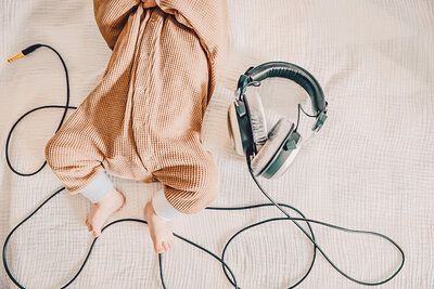 LIttle baby in jumpsuit next to headphones for storybook