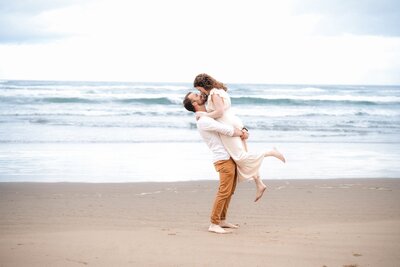 man lifting up his fiance on the beach