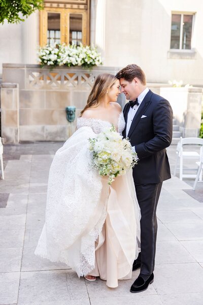 Couple facing each other with foreheads touching, bride in wedding dress and groom in tux,