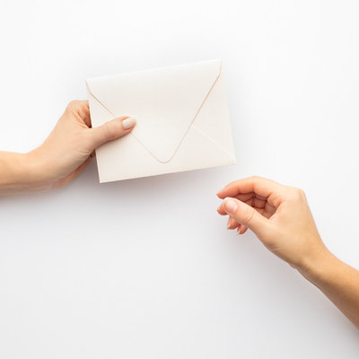 Two hands holding a closed white envelope
