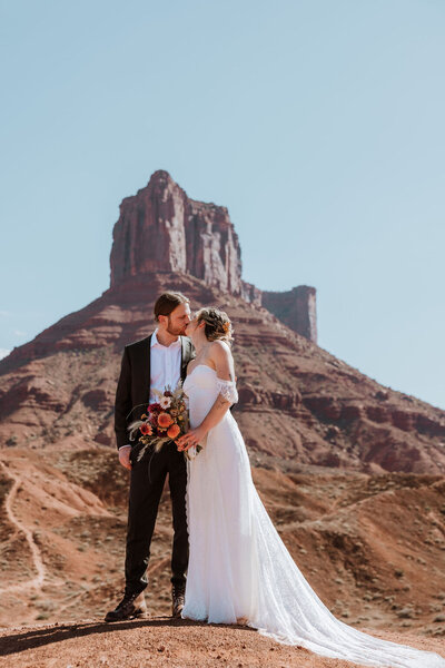 bride and groom kissing with a huge rock formation in the background