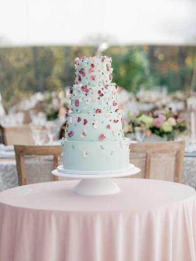 Wedding cake with floral decorations on a pink tablecloth.