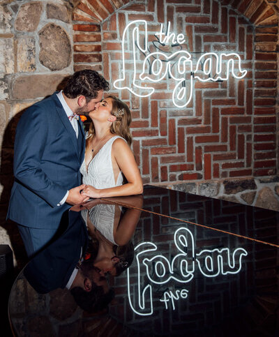 Groom kissing bride under neon sign at trendy bar | Logan Inn Wedding | New Hope, Pennsylvania