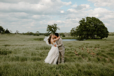 bride and groom kissing in an open field