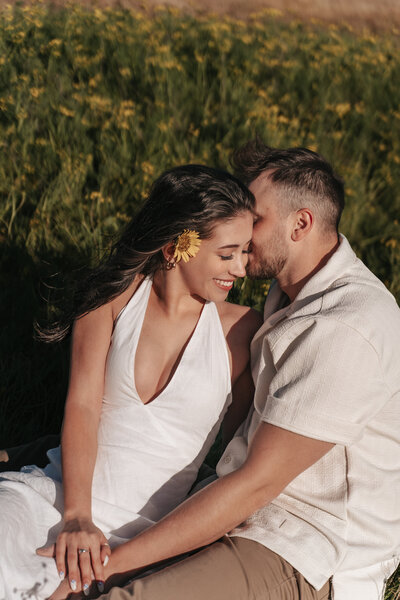 Romantic couple sharing an intimate moment in a vibrant field of yellow wildflowers during a golden hour photoshoot, captured by a Portland wedding photographer specializing in natural outdoor wedding and engagement sessions.