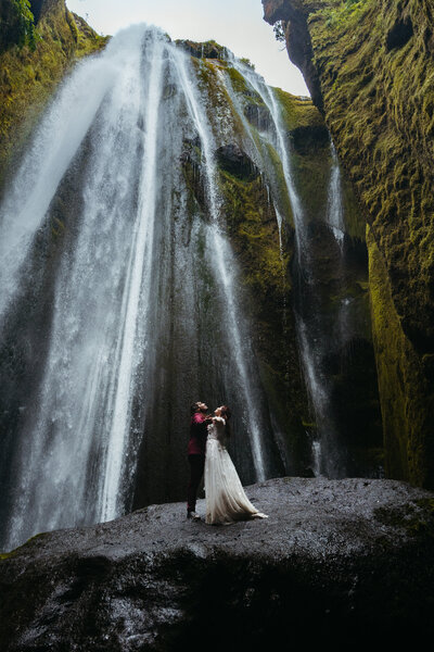 Gljufrabui Elopement Iceland couple standing under a waterfall