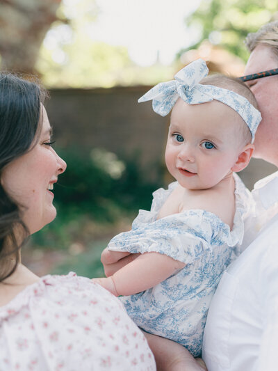 mom and dad holding baby walking