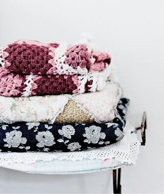 four blankets folded neatly and stacked on top of a shelf.