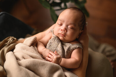 Newbprn baby sleeping with his arms crossed