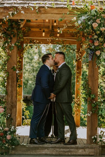 A same sex couple share a kiss at their wedding.