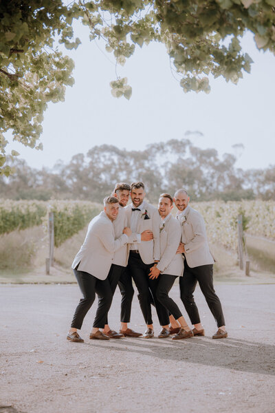 Groom and groomsmen hugging in a huddle and laughing