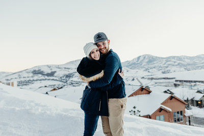 man & woman hugging and smiling in snow