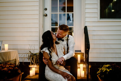 couple sitting on backdoor stairs kissing surrounded by romantic candles