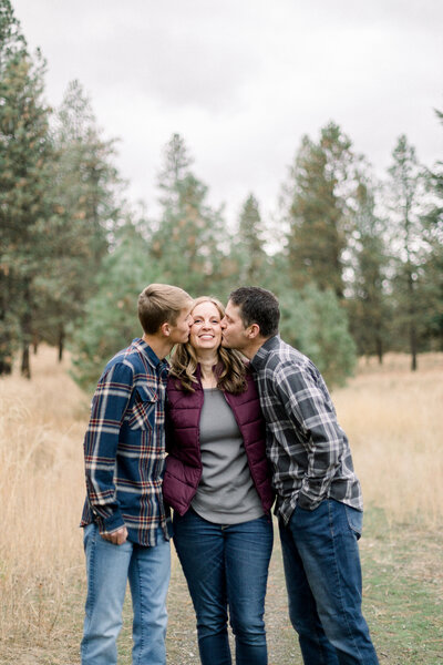 husband and son kissing mom and cheek while mom is smiling taken by Spokane Family photographer