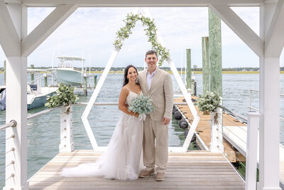 Bride and groom sharing a joyful moment on a waterfront dock, showcasing love and happiness against a scenic backdrop in Wrightsville Beach, North Carolina.